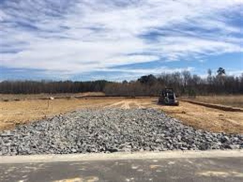 Gravel road leading to a dirt lot.